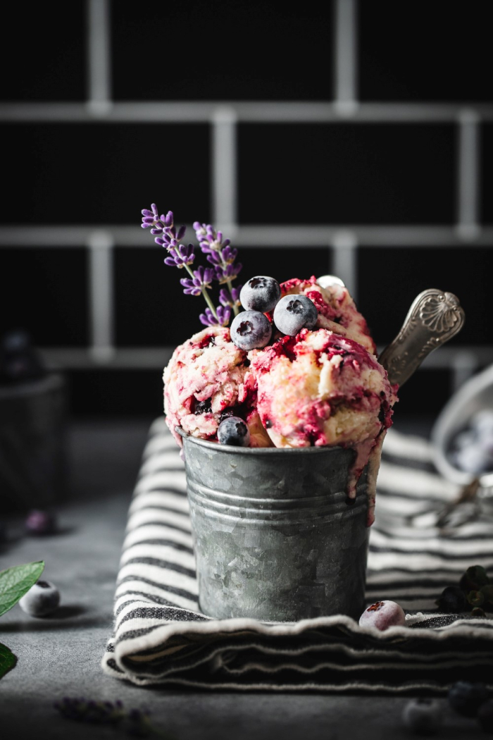 Blueberry ice cream in a metal cup decorated with frozen blueberries