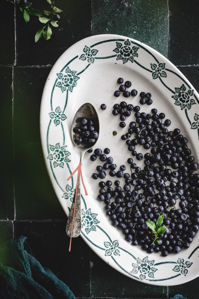 Forest blueberries on a vintage plate on a dark green backdrop