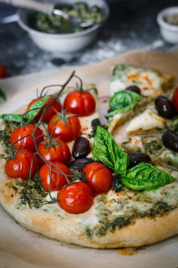 Italian flavors with a twist in one delicious spicy goat cheese pesto pizza loaded with fresh cherry tomatoes, mozzarella and black olives. I could eat this pizza every day!